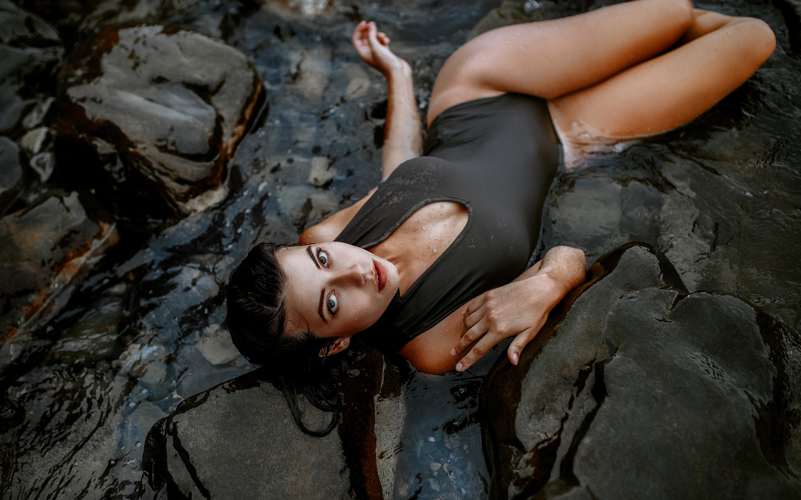 Обнаженная девушка в очках плещется в морской воде у каменных валунов порно фото