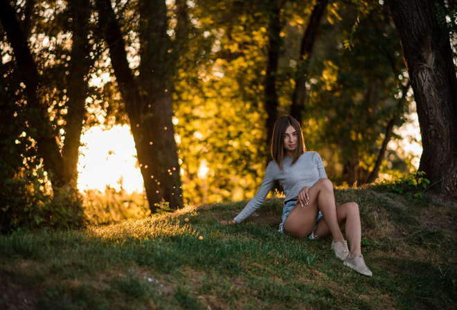 women, sitting, grass, trees, jean shorts, sneakers, smiling