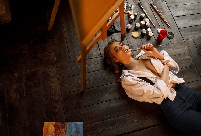 women, blonde, portrait, easel, white shirt, pants, jeans, painting, top view, lying on back, on the floor, wooden floor