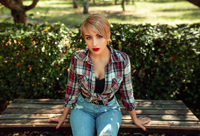 women, blonde, red lipstick, torn jeans, plaid shirt, trees, women outdoors, sitting, red nails, blue eyes, short hair, belt, bench, portrait