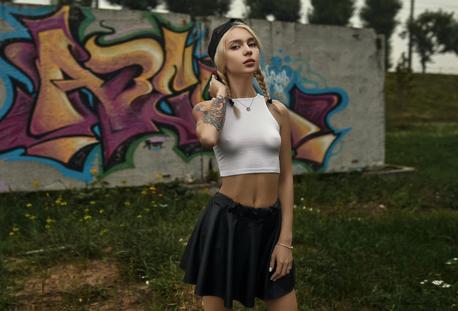 women, blonde, tank top, women outdoors, pigtails, baseball cap, wall, graffiti, grass, nipple through clothing, black skirts, tattoo, painted nails, eyeliner, belly, trees