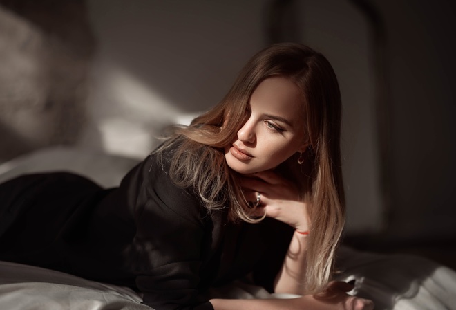 women indoors, in bed, blonde, , black pants, model, lying on front, jacket, black clothing, black jacket