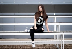 women, sitting, T-shirt, pants, torn jeans, black clothing, sneakers