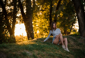 women, sitting, grass, trees, jean shorts, sneakers, smiling