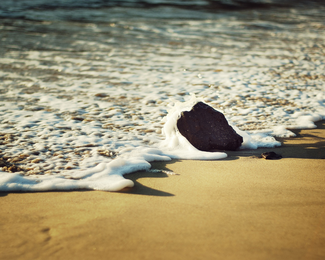 Море берегом пенится. Море пляж. Берег моря песок. Камни на песке. Пляж макро.