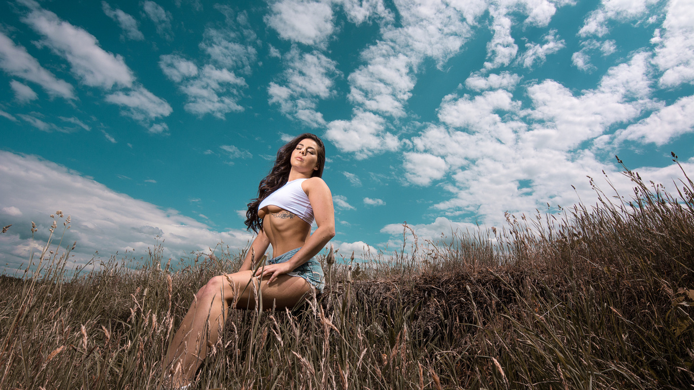 women, closed eyes, underboob, t-shirt, sitting, women outdoors, sky, clouds, tattoo, long hair, wavy hair, belly, brunette, boobs, jean shorts