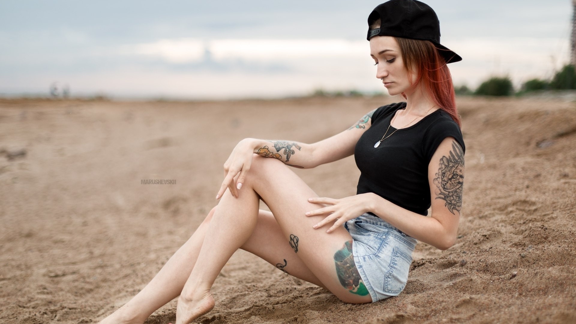 julia tyki, women, skinny, baseball caps, sitting, dyed hair, jean shorts, sand, nose rings, necklace, depth of field, tattoos