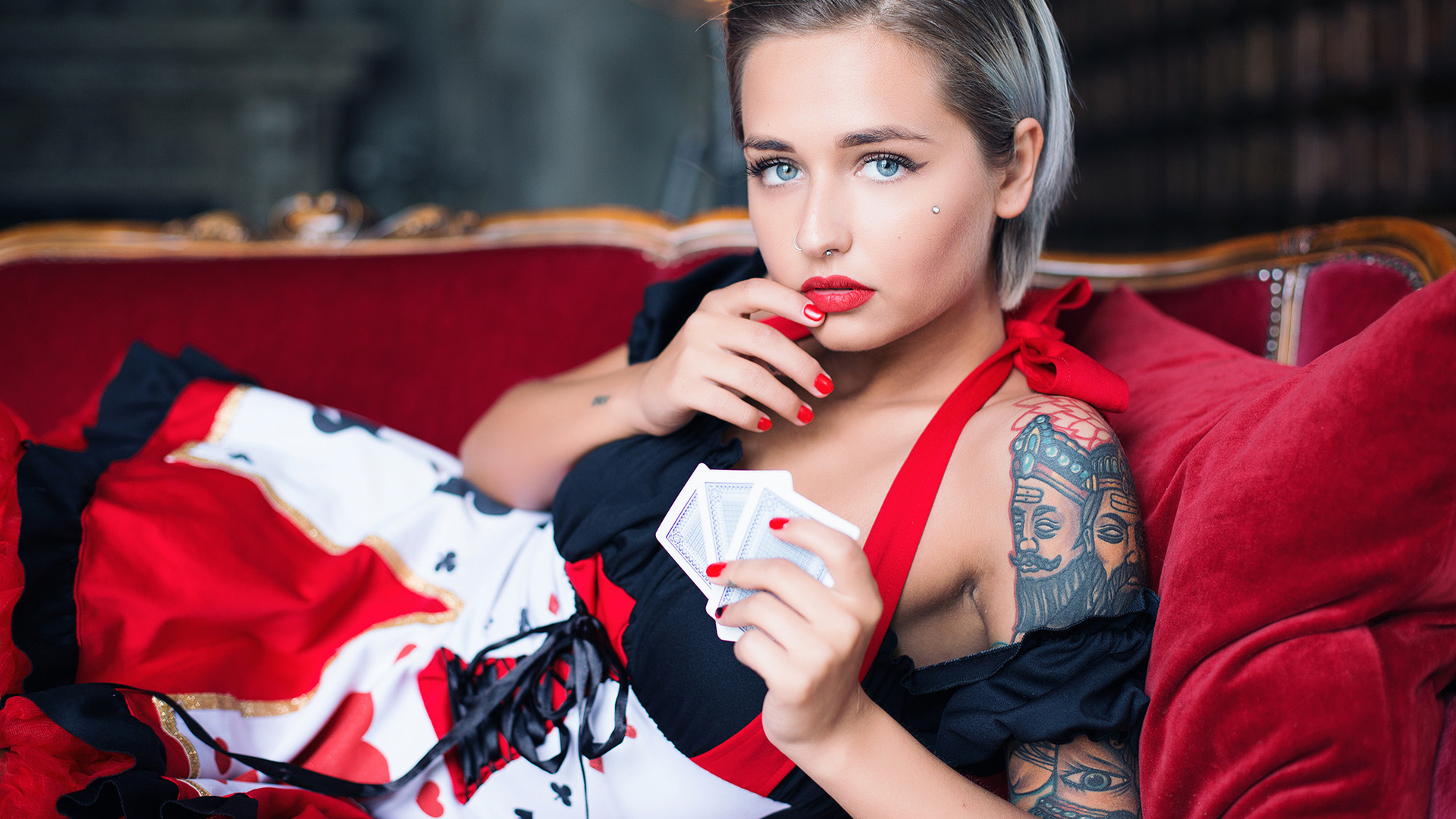 women, portrait, dress, red nails, blue eyes, tattoo, red lipstick, short hair, couch, nose rings, piercing, playing cards, depth of field