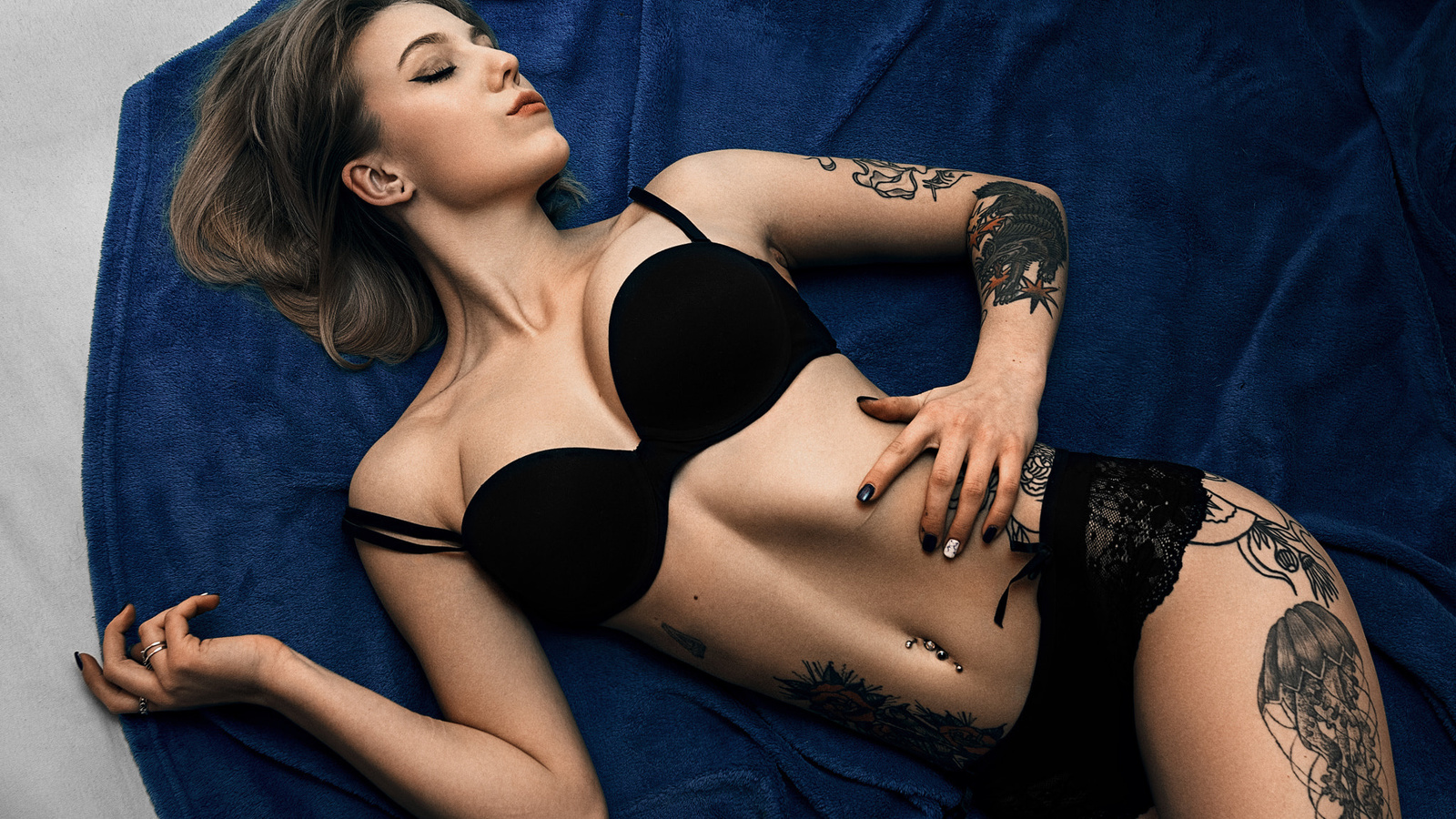 women, brunette, top view, black lingerie, tattoo, belly, pierced navel, closed eyes, painted nails, eyeliner