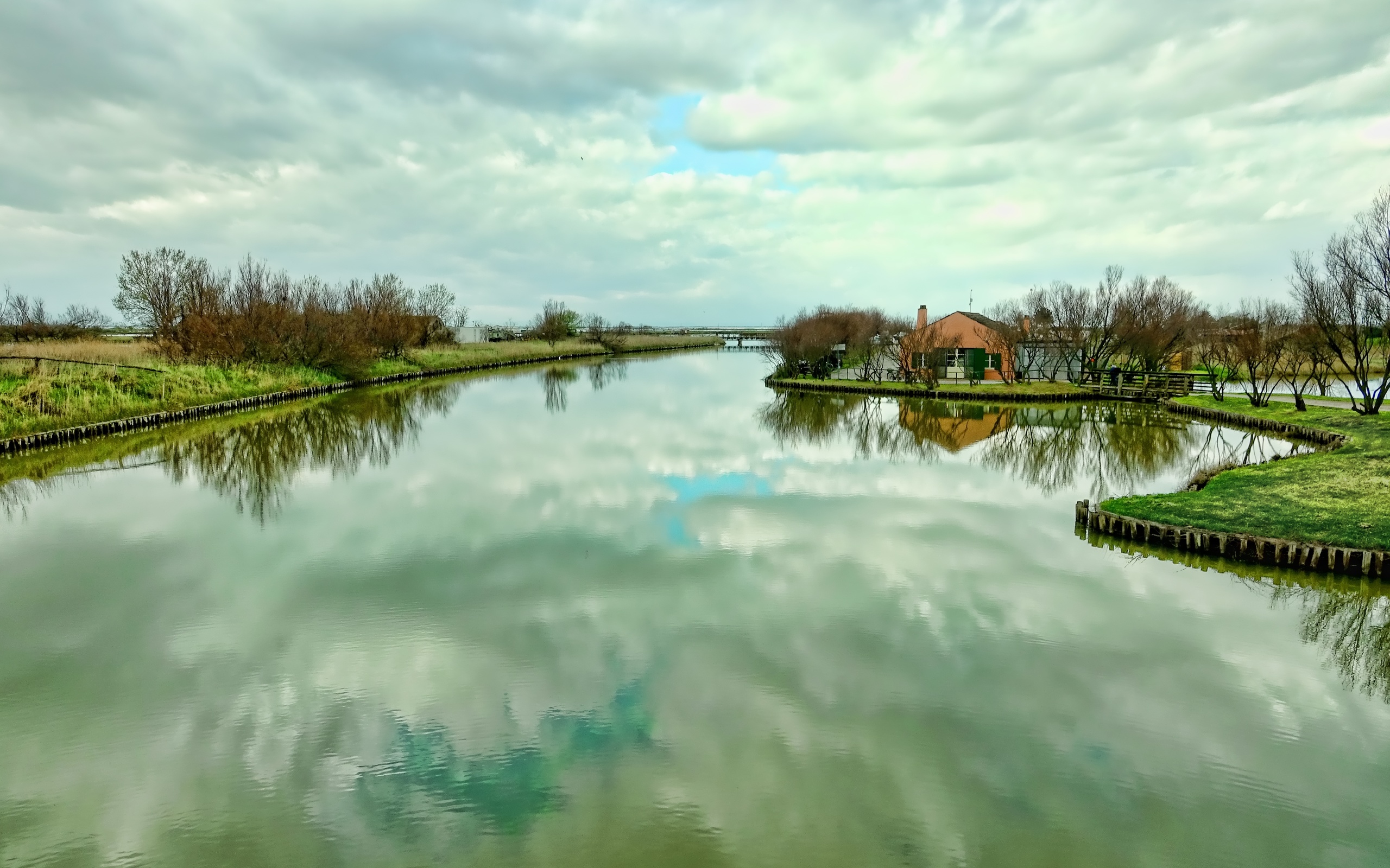 Поверхностные реки. Поверхность реки. Фото домов, отражающихся в воде весной и летом. The Bank of the River in cloudy weather.