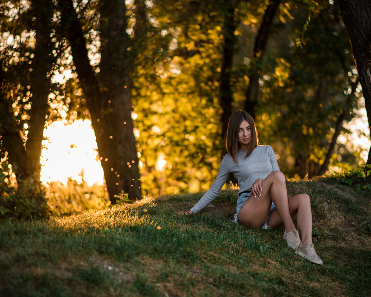 women, sitting, grass, trees, jean shorts, sneakers, smiling