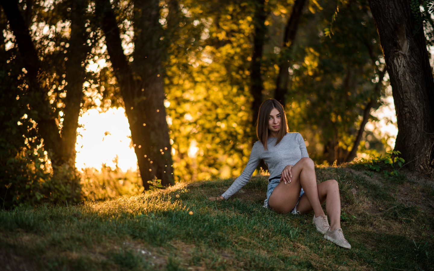 women, sitting, grass, trees, jean shorts, sneakers, smiling