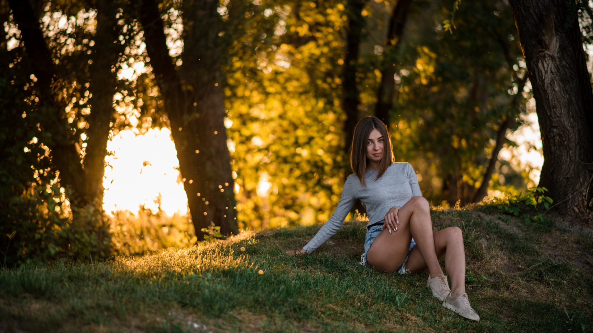 women, sitting, grass, trees, jean shorts, sneakers, smiling