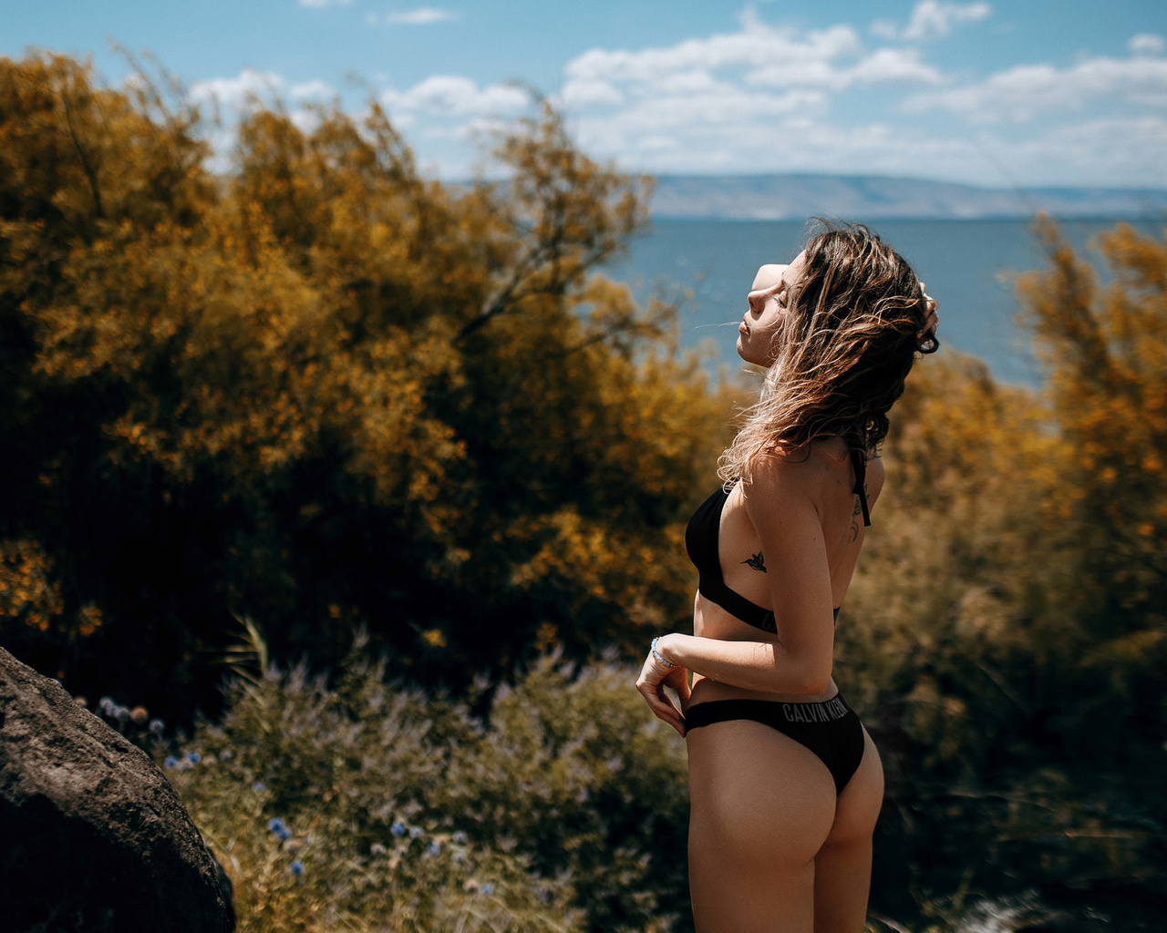 women, calvin klein, ass, brunette, tattoo, women outdoors, sea, rocks, sideboob, swimwear, sky, clouds, closed eyes