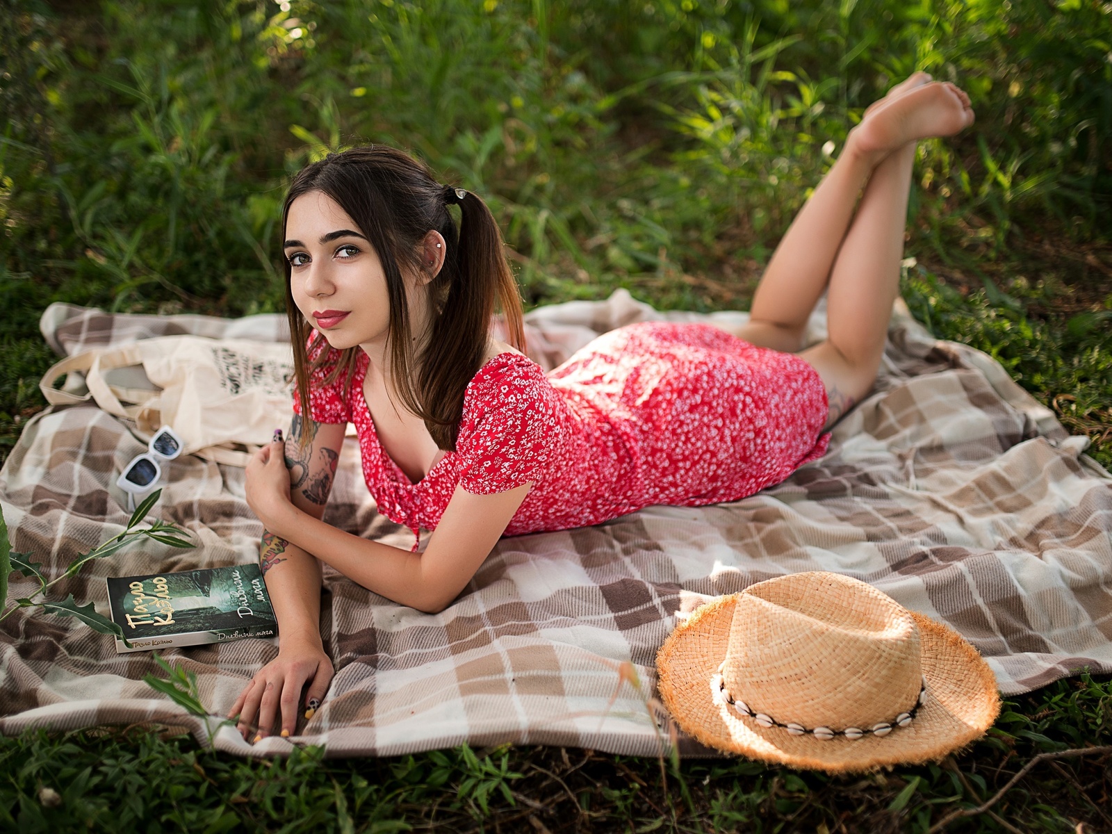 brunette, model, women, women outdoors, summer dress, tattoo, picnic, straw hat, sunglasses, glasses, lying on front, dress, barefoot, pierced ear, books, trees, grass, twintails