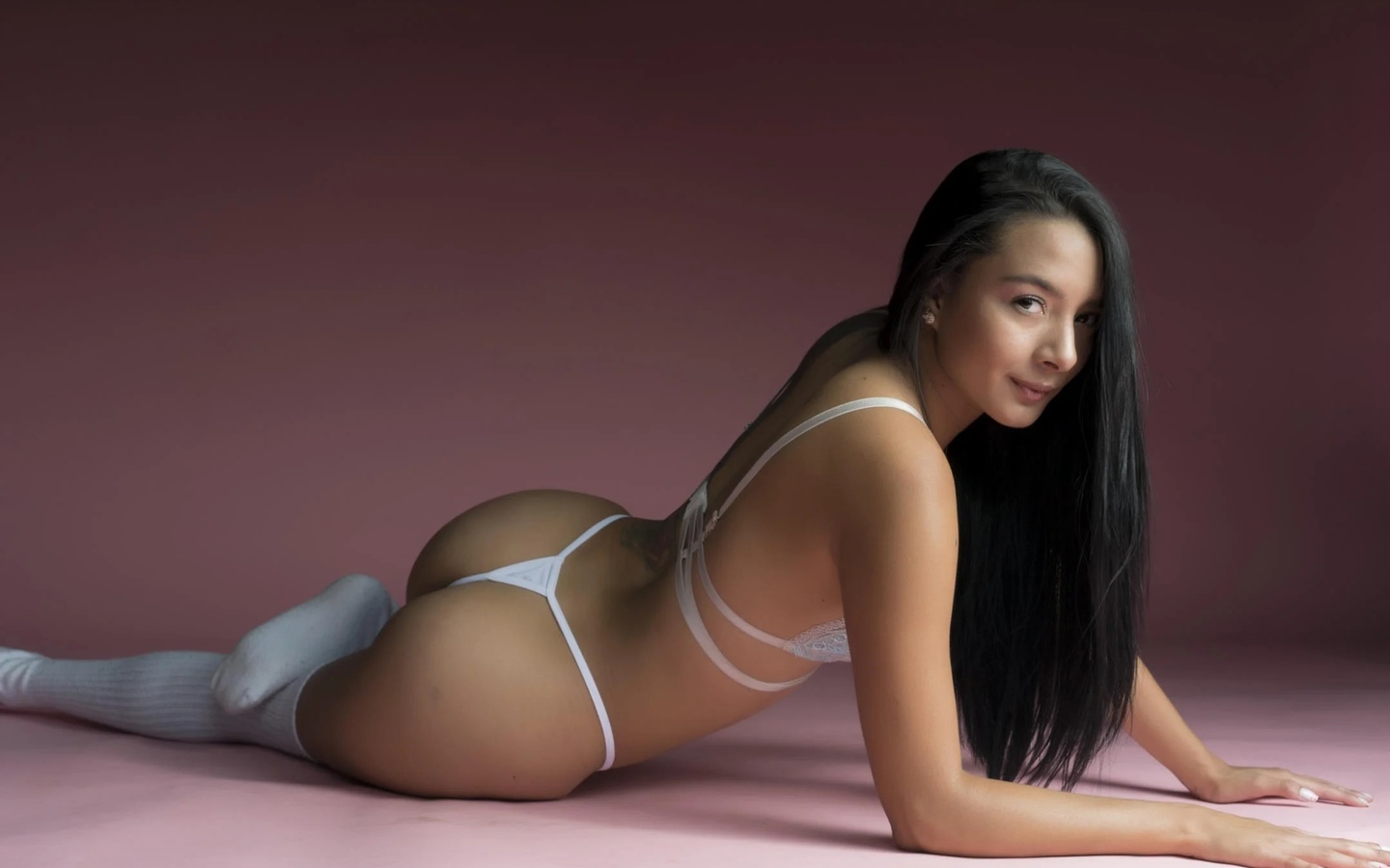 studio, brunette, ass, , women indoors, white panties, tattoo, lingerie, model, thigh-highs, hips, on the floor, pink background, long hair, white thong