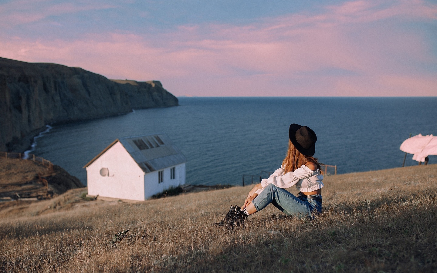 women outdoors, jeans, sea, , brunette, grass, nature, sky, model, clouds, black hat, cottage, boots, white blouse, white tops, white tops, landscape