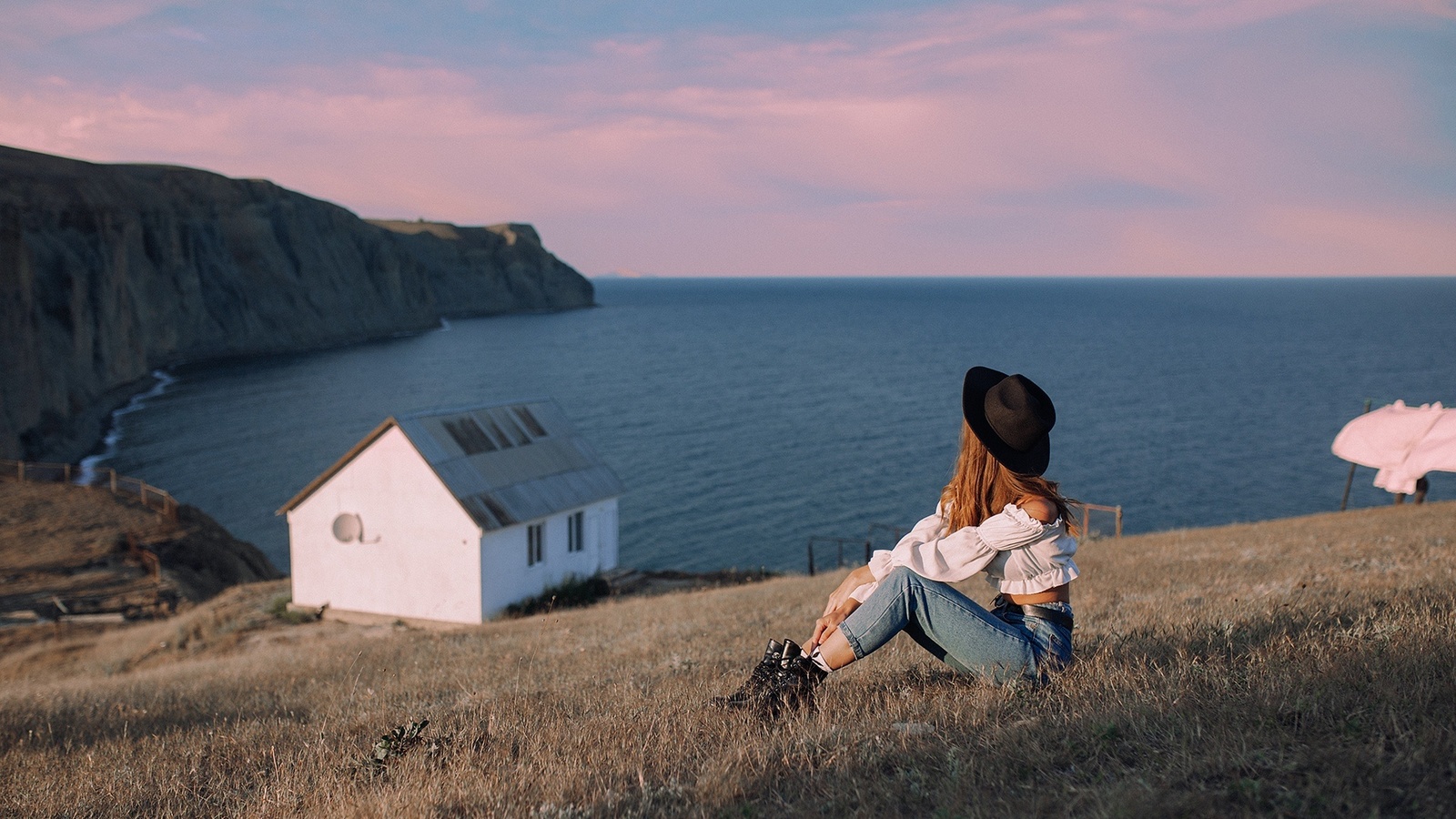 women outdoors, jeans, sea, , brunette, grass, nature, sky, model, clouds, black hat, cottage, boots, white blouse, white tops, white tops, landscape